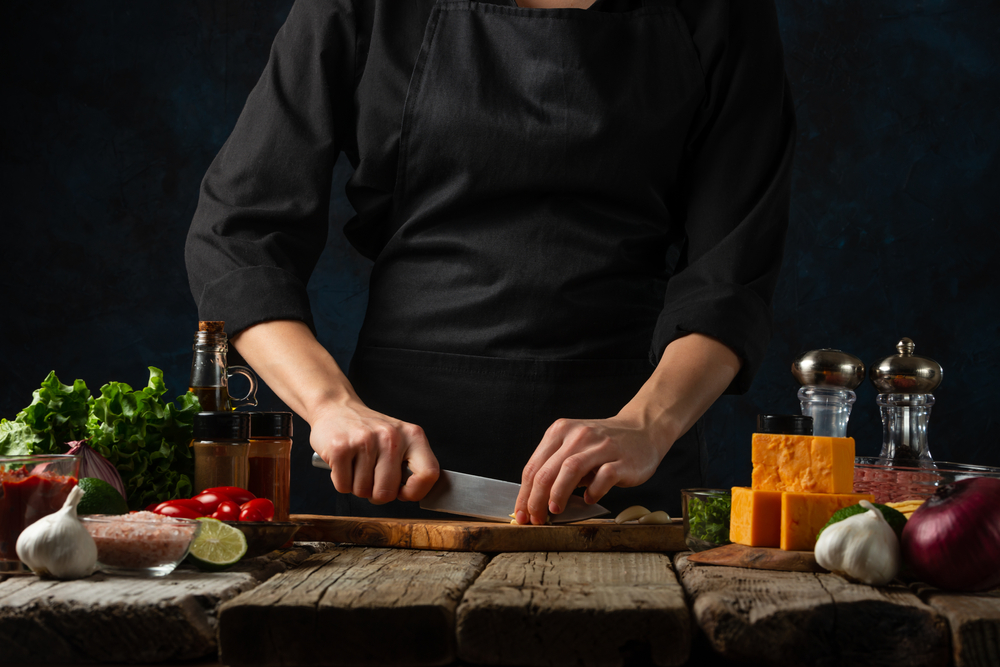 Professional,Chef,In,Black,Uniform,Cuts,With,Knife,Garlic,On